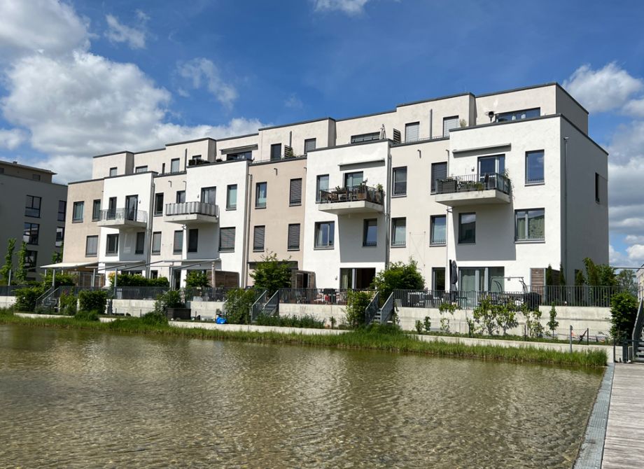 Moderne Wohnanlage am Wasser in Berlin mit Balkonen und Terrassen bei blauem Himmel
