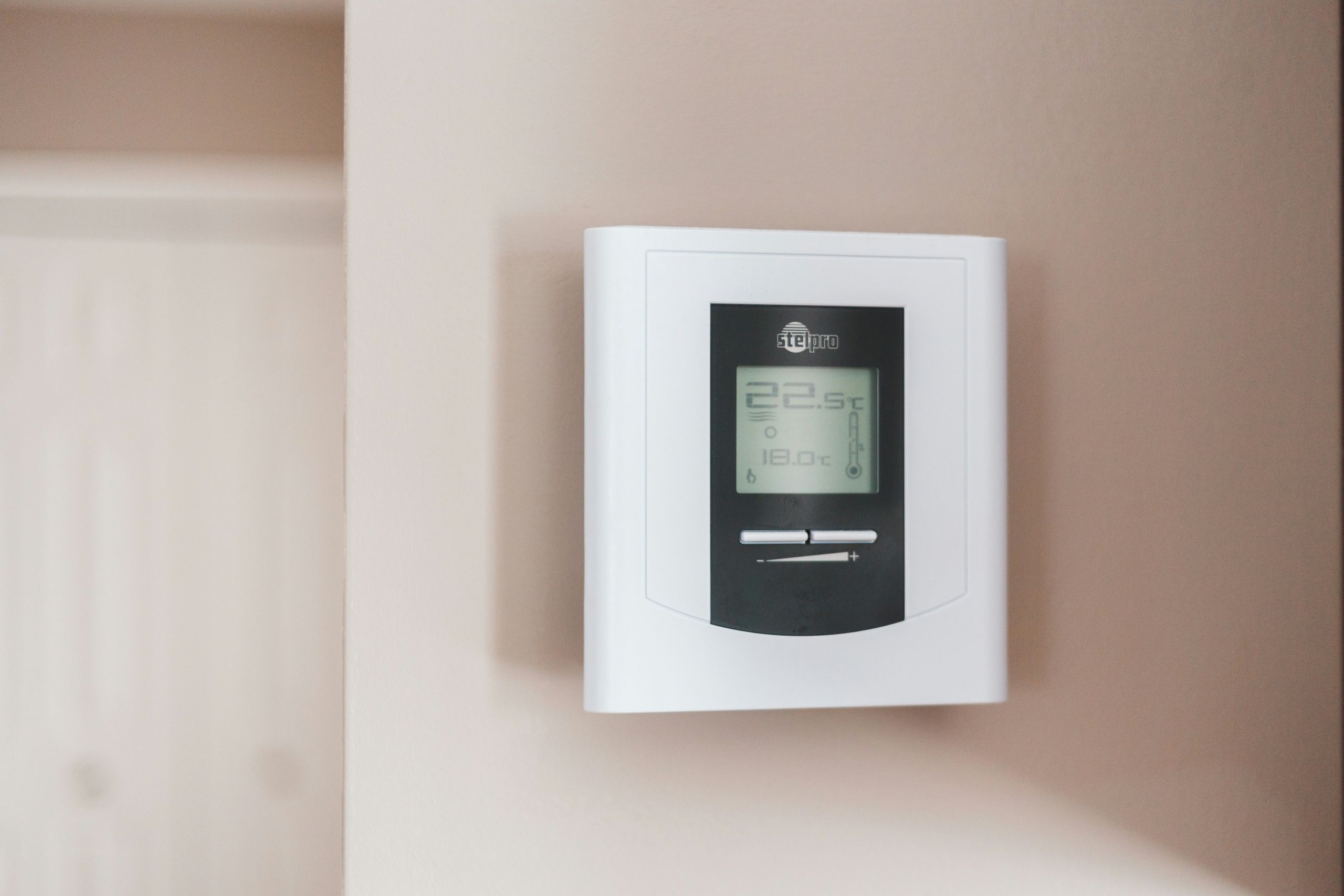 Digitales Thermostat an der Wand als Symbol für energieeffizientes Heizen in Wohnimmobilien