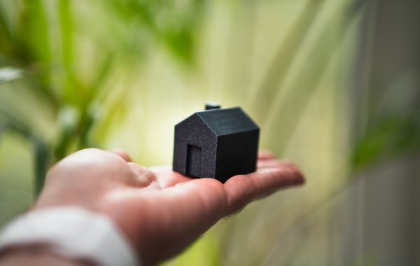 Kleines Hausmodell in der Hand als Symbol für Immobilienverwaltung und Werterhalt