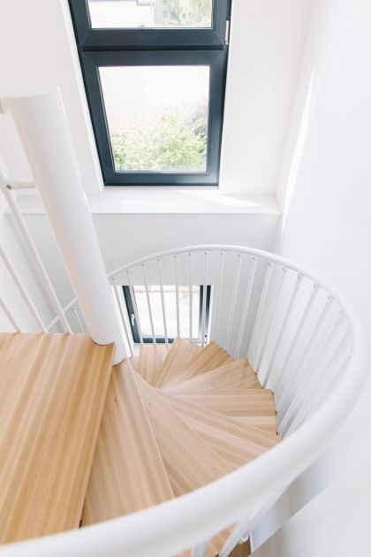 Helle Wendeltreppe mit Holzstufen in moderner Wohnimmobilie