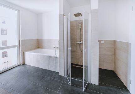 Helles Badezimmer mit Badewanne, Glasdusche und modernen Fliesen in einer Wohnimmobilie